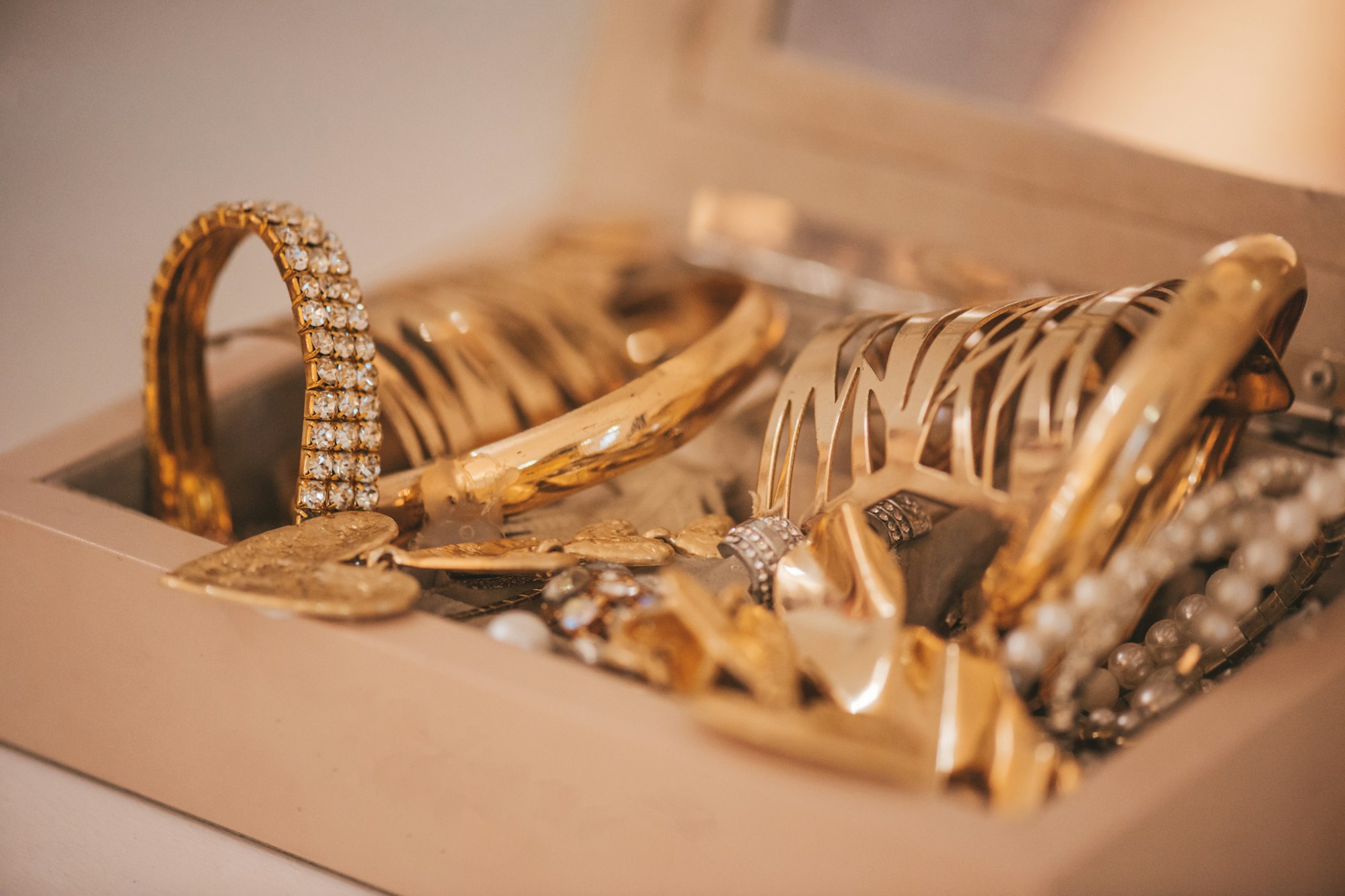 Luxury gold jewelry on set holders and in jewelry box on light dressing table and wardrobe shelves